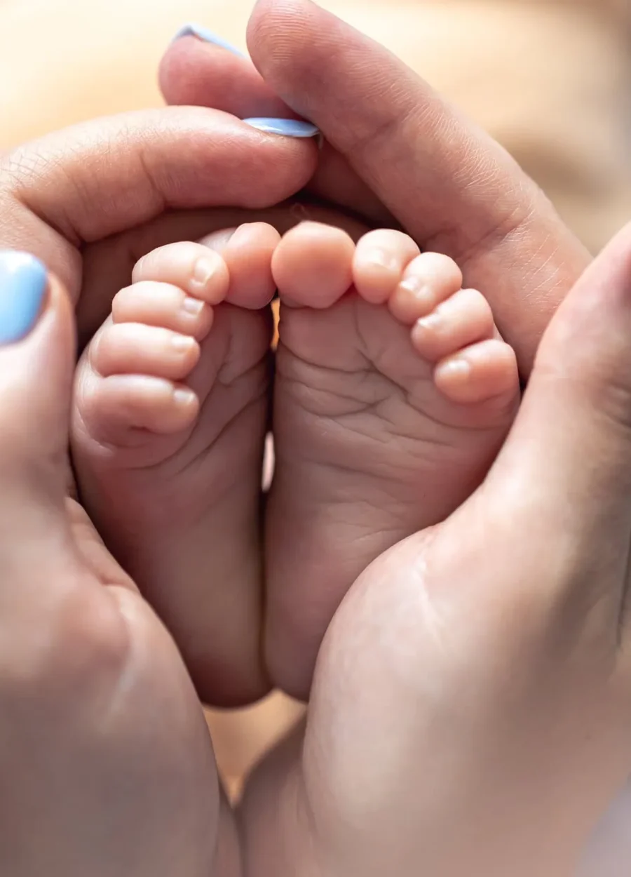 mom-holds-legs-newborn-baby-her-hands