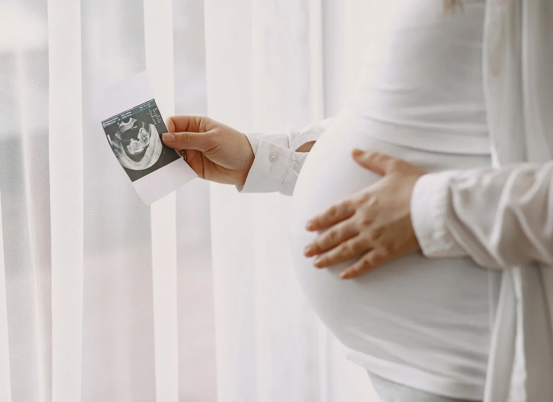pregnant-woman-standing-by-window-looking-photo